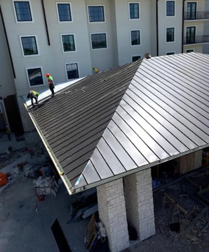 Crew installing standing seam metal roof panels on a commercial project in Juneau